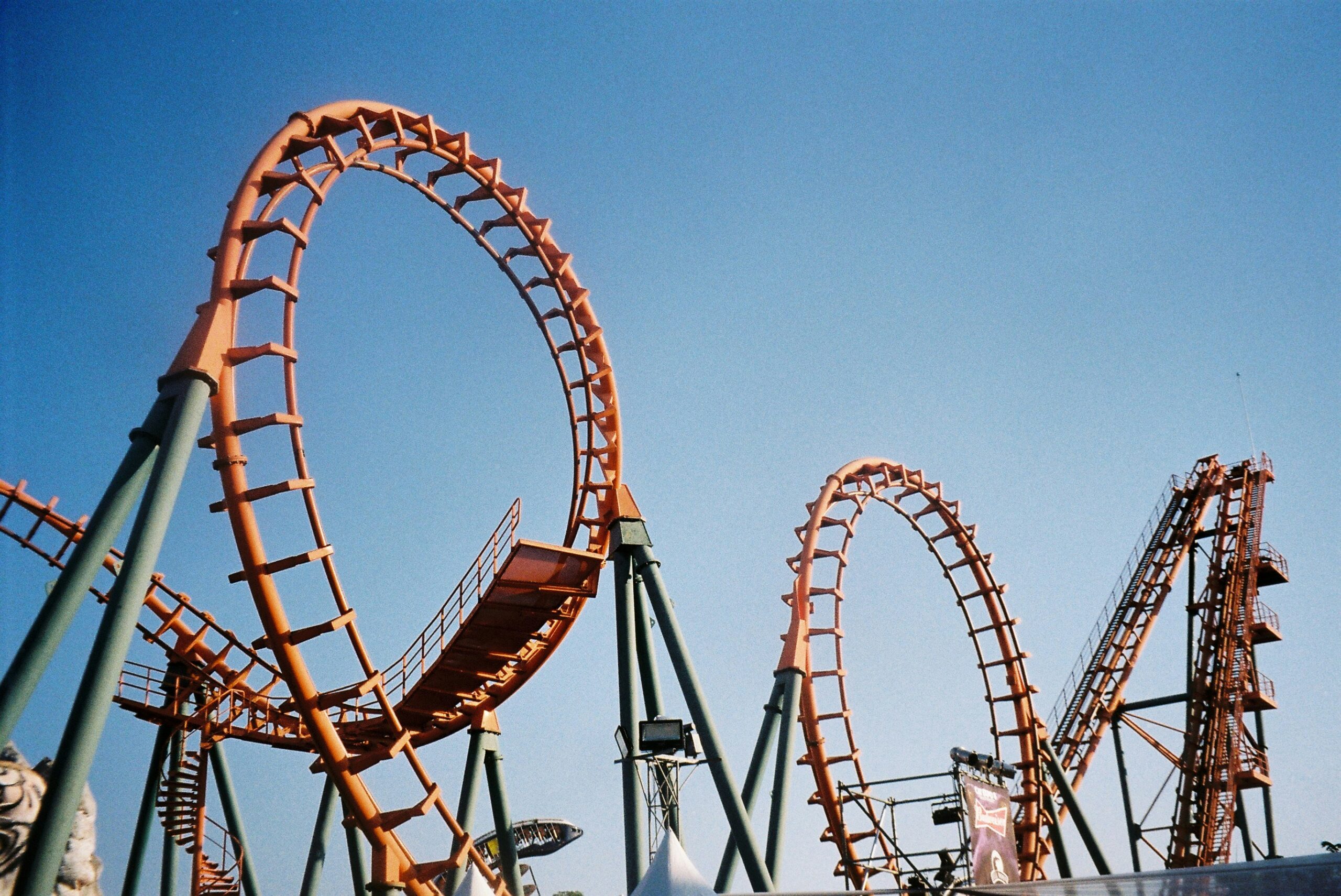 Orange roller coaster against blue sky.