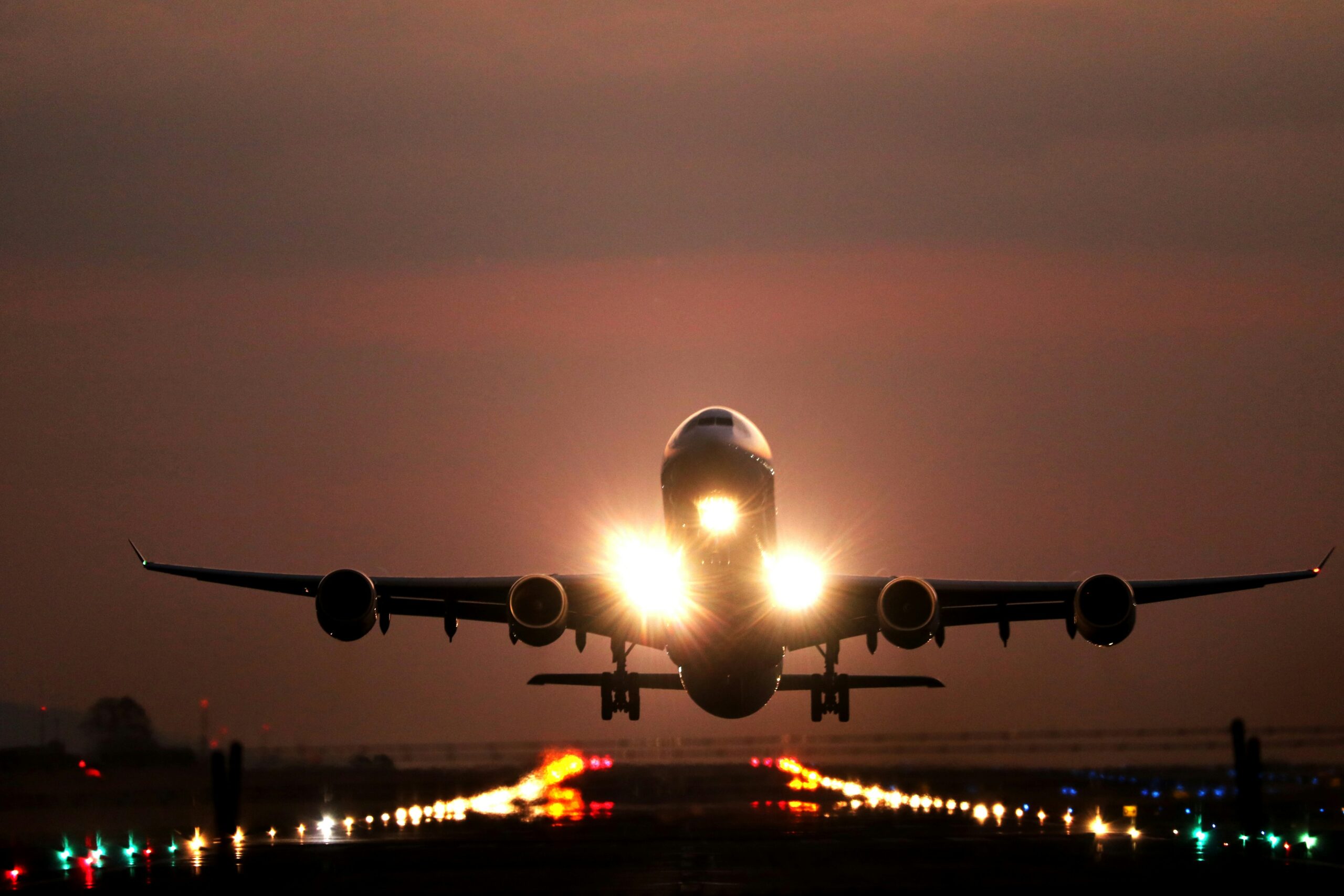 Plane taking off a night with lit up runway.