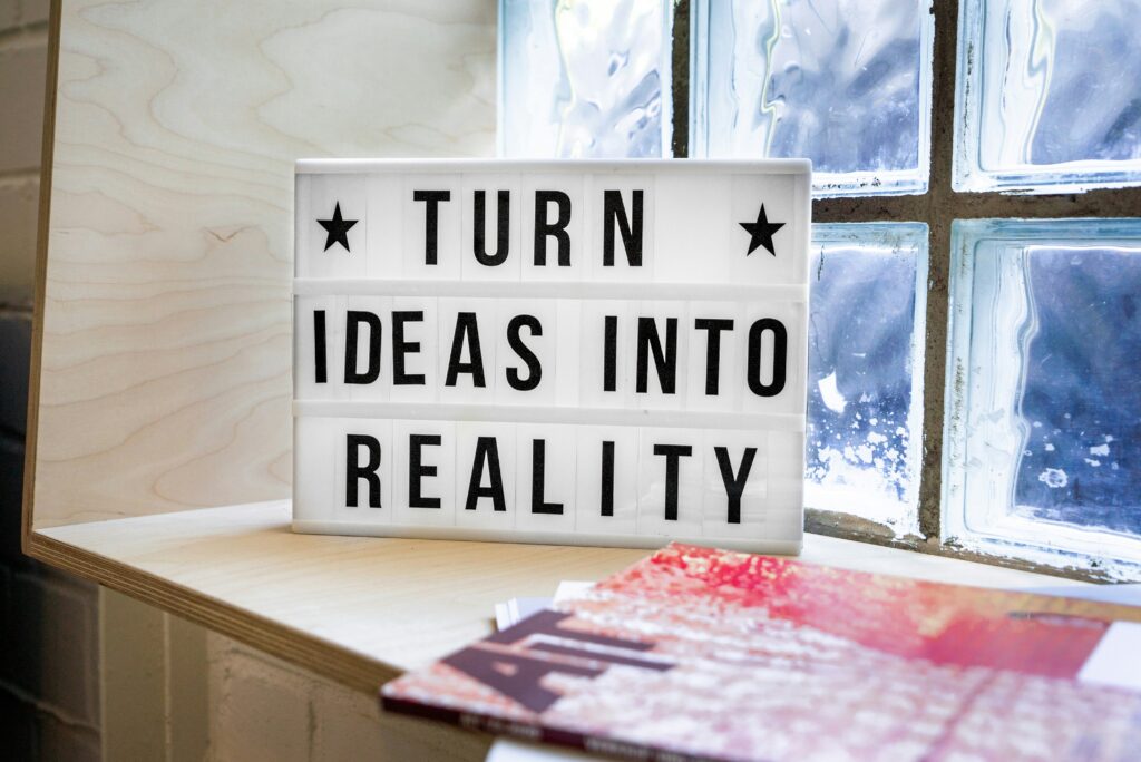 Sign that says 'Turn ideas into reality' on window seat in front of clad window with black trim.